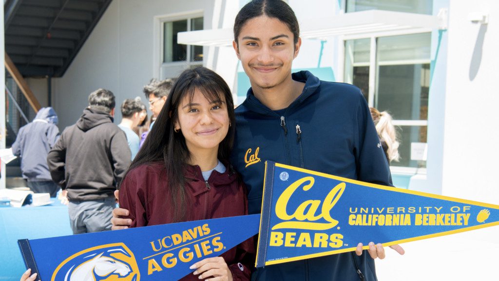 Two students holding UC Davis and Cal flags at Making Waves Academy campus