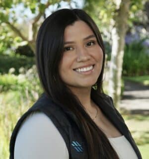 Leticia smiling for her headshot with greenery in background