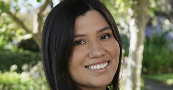 Leticia smiling for her headshot with greenery in background