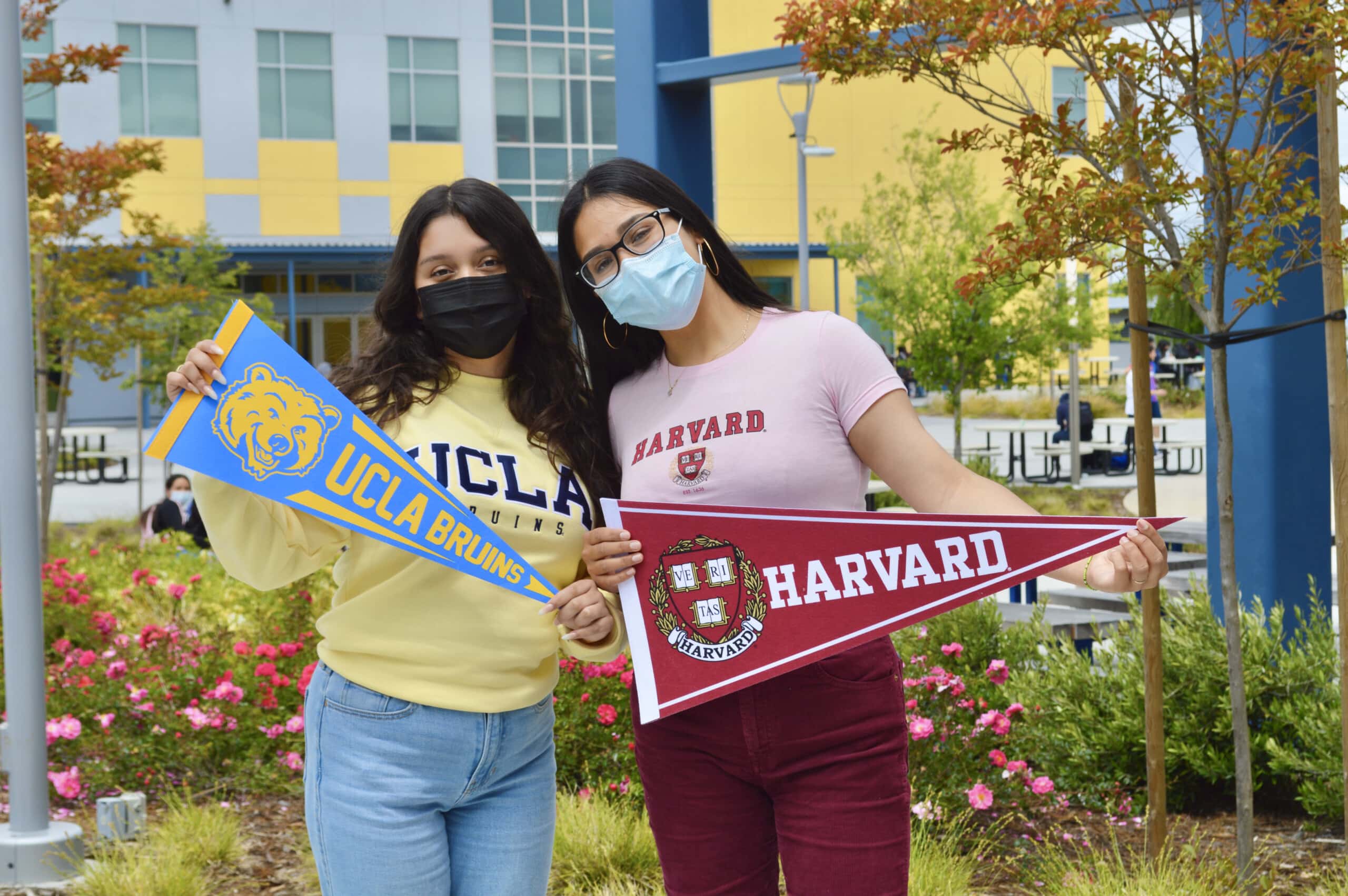 Students holding UCLA and Harvard flags at Making Waves Acamdey campus