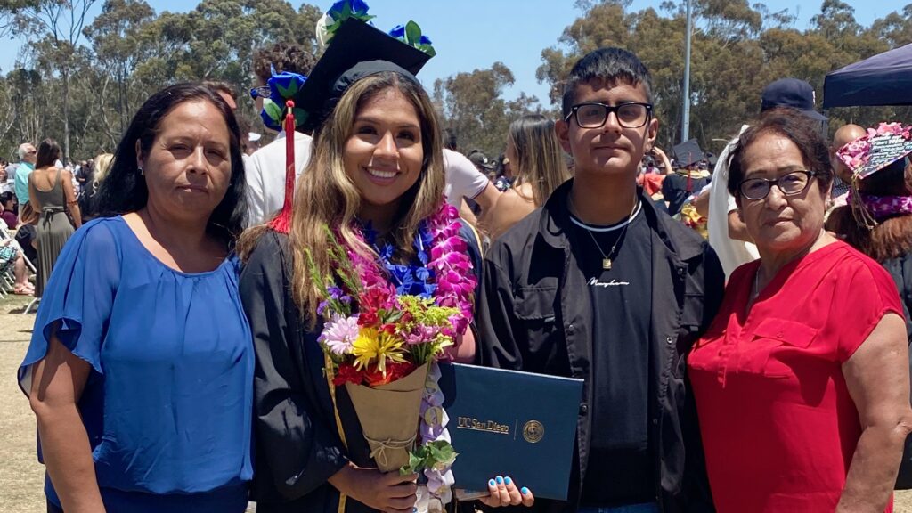 Allison holding diploma at graduation with her family 