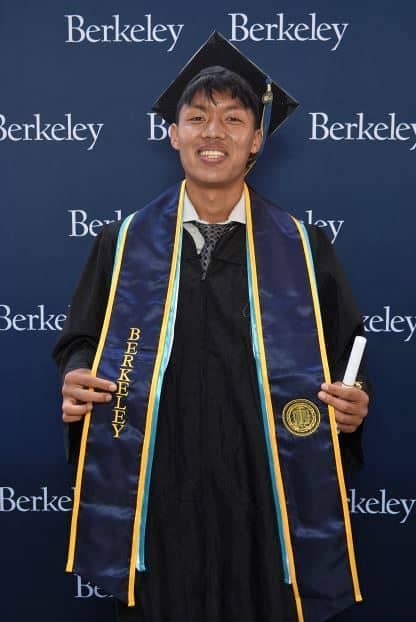 Diraj Thajali in his cap and gown with a UC Berkeley backdrop