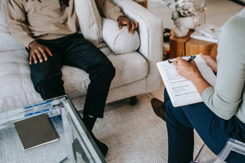 Photo of a man sitting on a couch while getting some counseling