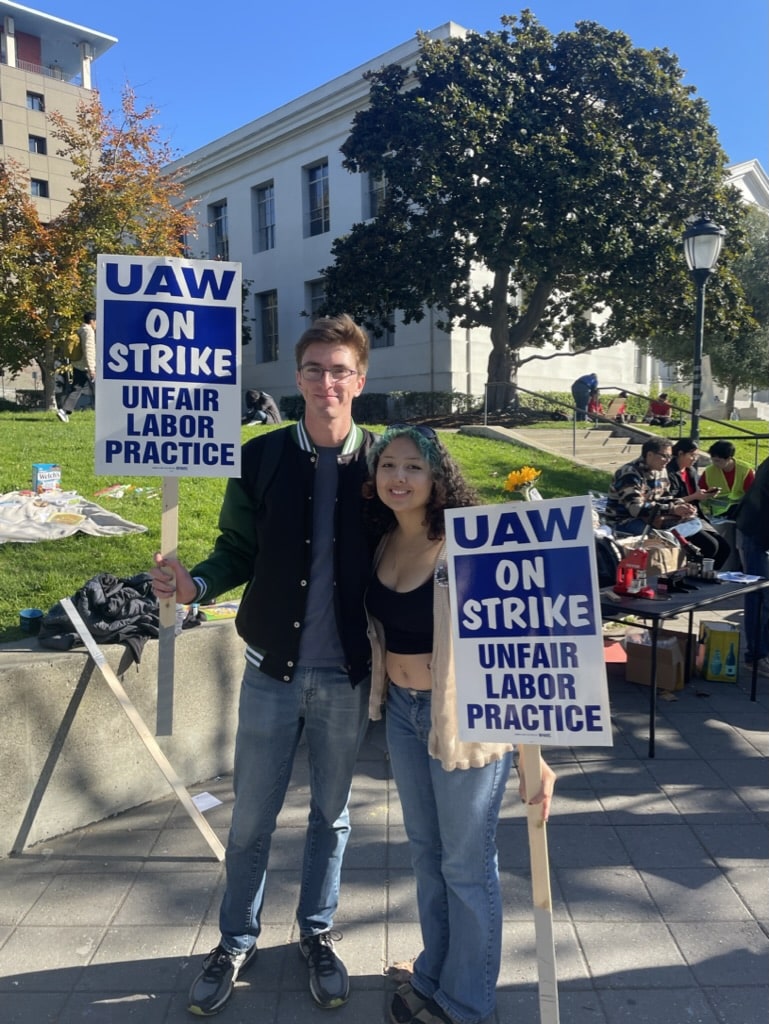 Ale holding UAW on strike sign with another student also holding a sign on UC Berkeley campus