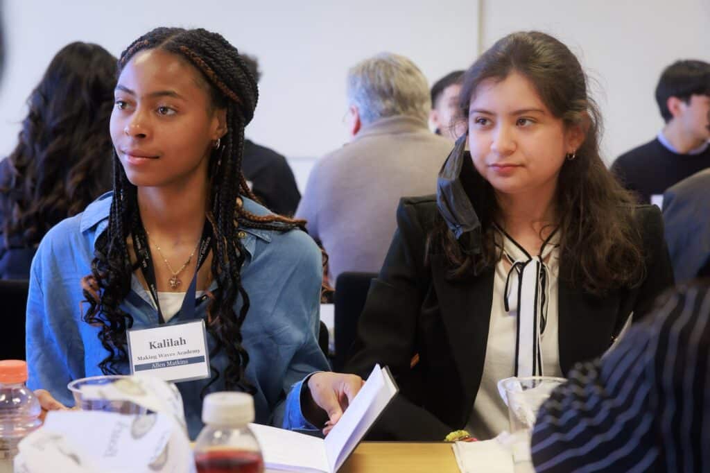 Two students look over at a speaker across the table