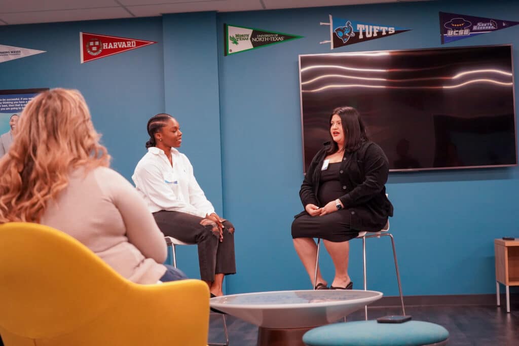 Ashley and Jackie sitting in chairs talking in front of audience