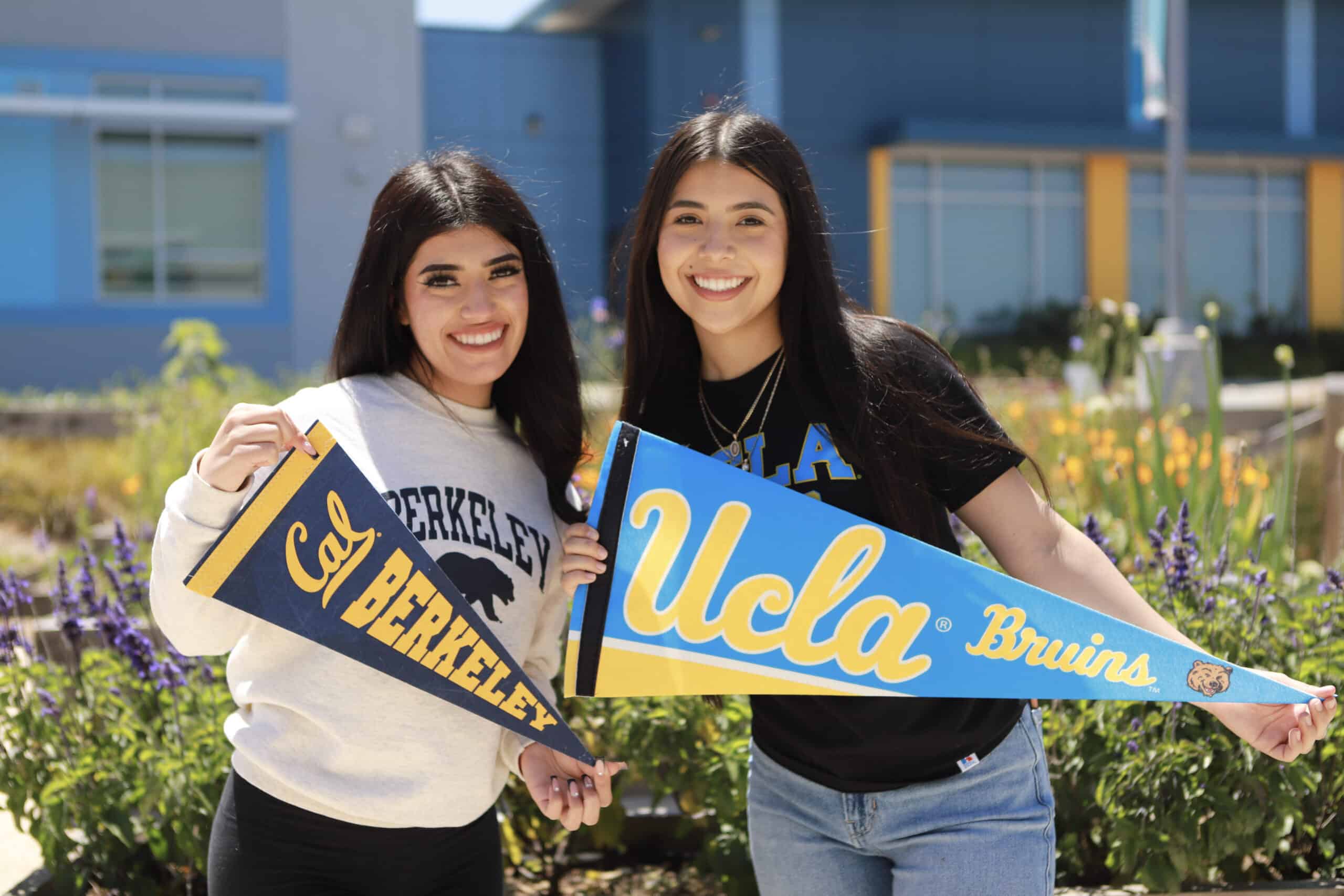 Two students holding UC Berkeley and UCLA flags