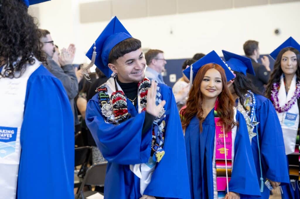 Students in blue caps and gowns walking into graduation