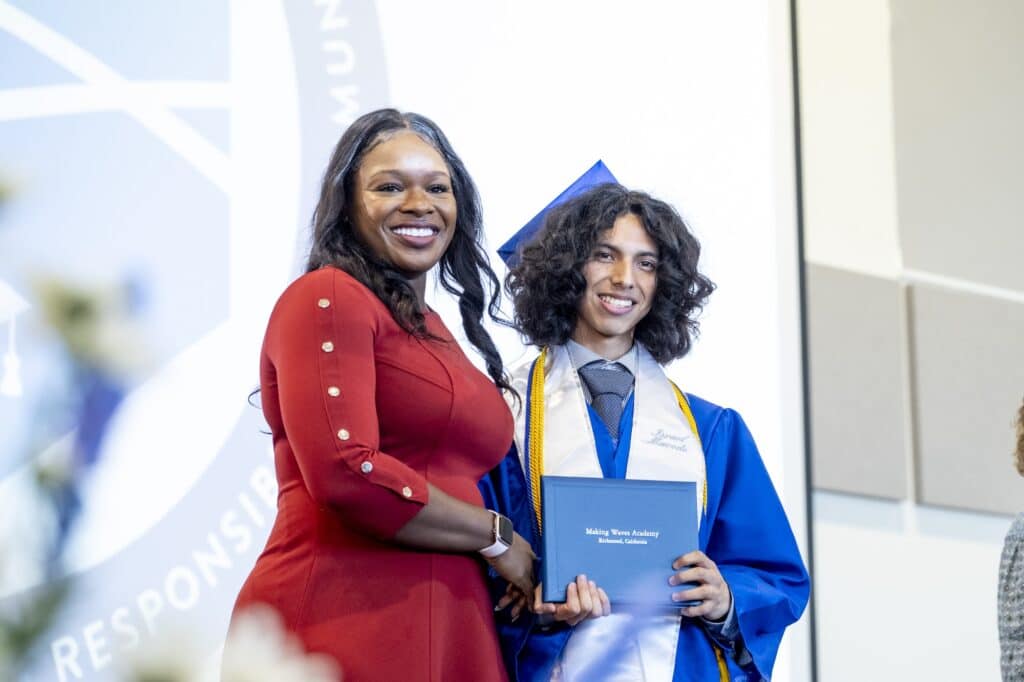 Principal smiling with student holding diploma