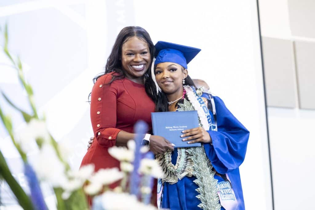 Principal smiling with student holding diploma