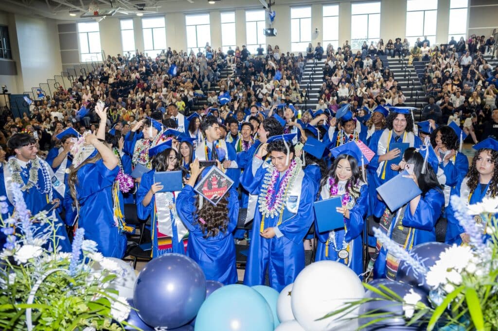 A crowd celebrating graduation wearing blue caps and gowns