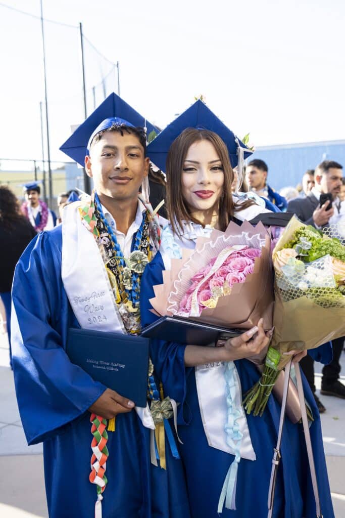 Photo of two students together holding flowers