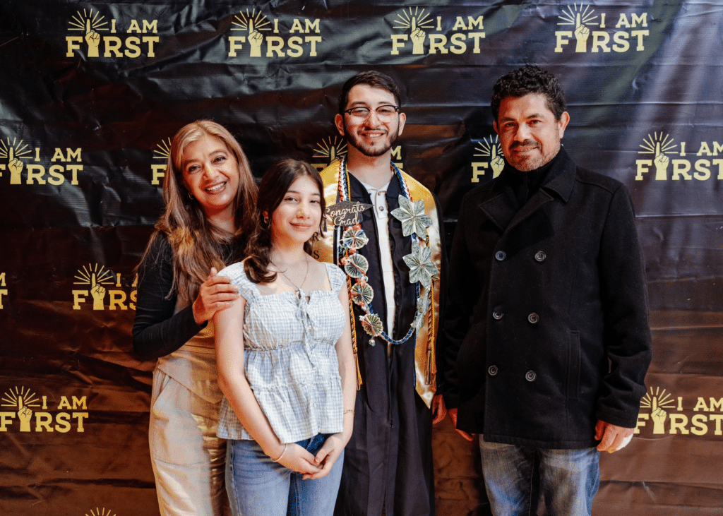 Estefan Cervantes and 3 family members stand in front of a First gen graduation step and repeat smiling