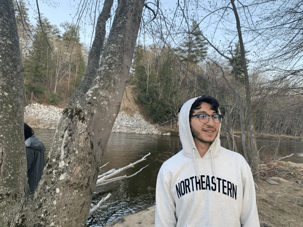 Estefan Cervantes in gray Northeastern college sweatshirt next to a tree