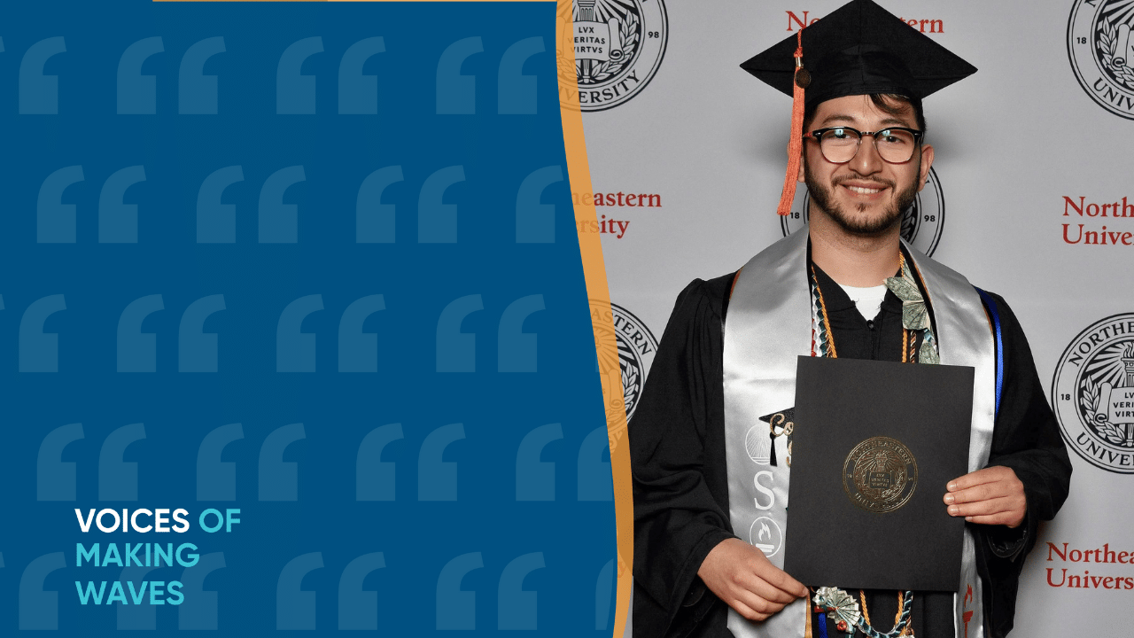 Photo of Estefan in grad cap and gown smiling holding diploma in front of Northeastern banner